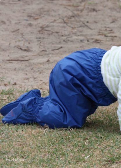 close up of blue muddlarks® crawler pants on girl while she crawls on sand