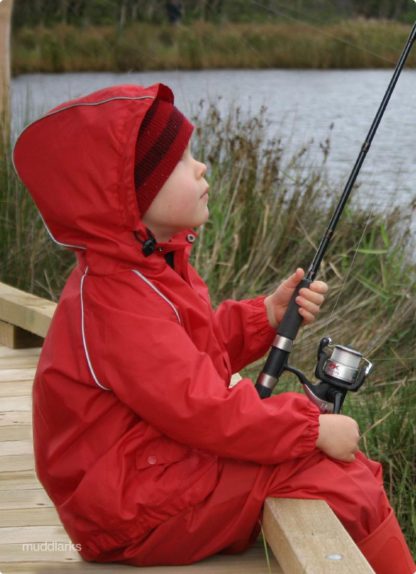 Boy fishing from boardwalk wearing muddlarks® waterproof lark jacket and muddlarks® waterproof pants