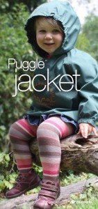 Girl sitting on log wearing green waterproof muddlarks® puggle jacket with hood on