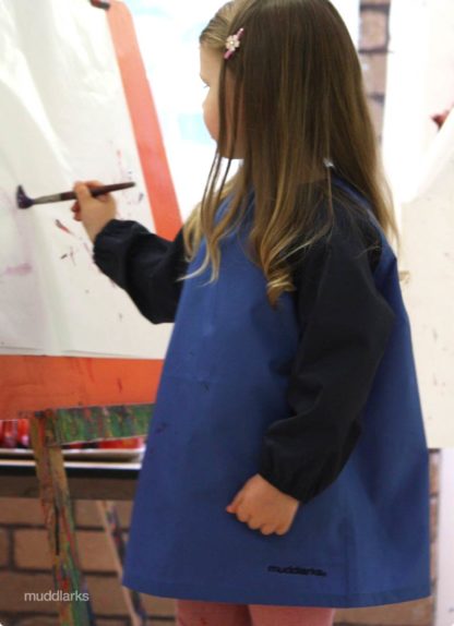 Girl painting wearing blue Muddlarks smock